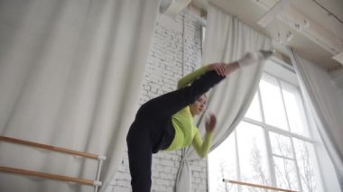 Vogue elementleri ve çağdaş bale gösterisi güzel bir kız tarafından bir dans stüdyosunun tuğla duvarına karşı sahnelendi.