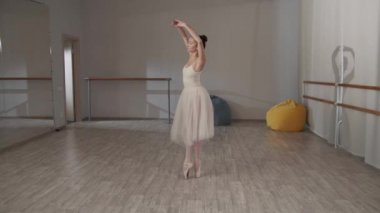 Dans salonunda büyüleyici bir balerin aynanın önünde güzel bir elbiseyle piruet yapıyor.