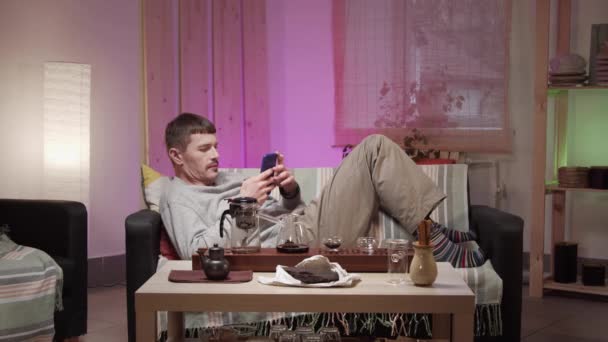 Mężczyzna w domu w kwarantannie rozmawia z przyjacielem w sieci społecznościowej i robi ceremonię herbaty z prawdziwą chińską herbatą. — Wideo stockowe