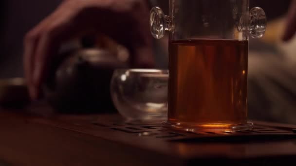 Primer plano de un vendedor de té que se prepara para celebrar una ceremonia de degustación de té en su tienda. Coloca tazas, una tetera de porcelana y un frasco de té en el chaban.. — Vídeo de stock