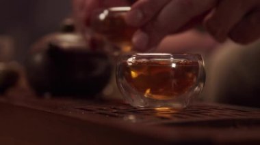Misafirperver ev sahibi, konuğa cam bir kaseden lezzetli Japon çayı ikram eder. Yüzü olmadan yakın plan..