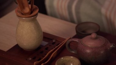 Çay seremonisi masasının panoramik görüntüsü. Tabakların hepsi dolu. Bardaklar, kaseler, kilden yapılmış bir çaydanlık, çay maşası ve bir kasede kurutulmuş çay yaprağı. Yavaş çekim.