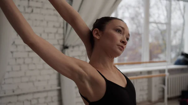 Baletka začíná zkoušku tím, že napne svaly u okna v tanečním sále, detailní záběr — Stock fotografie