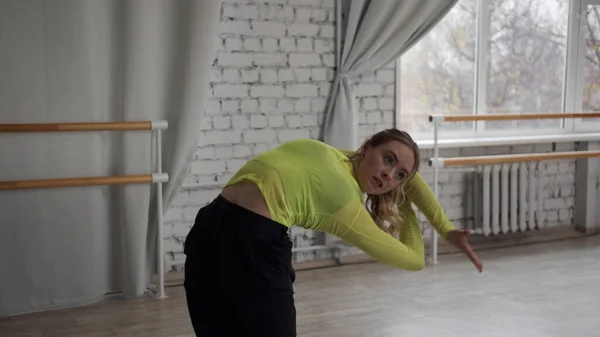 Dans le couloir, une jeune fille souple danse par la fenêtre, elle fait de beaux mouvements avec ses mains et ses pieds, démontrant des étirements — Photo