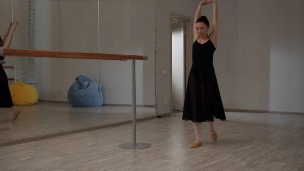 Une ballerine entre dans la salle de bal et commence à étirer les mains avant de répéter — Photo