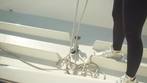 Блондинка з довгим волоссям розтягує мотузки яхт через блоки на палубі, щоб підготувати яхту до змагань . — стокове відео