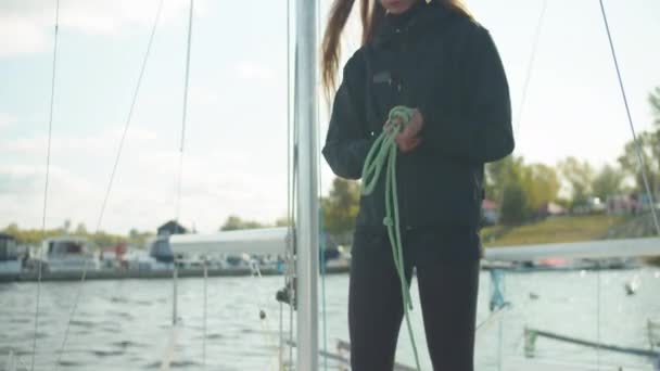 Krásná dívka na palubě bílé jachty plete mořský uzel na laně v přípravě na rafting na řece pod plachtou — Stock video