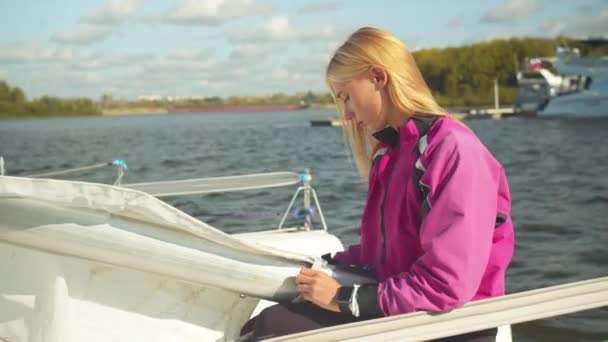 Hezká dívka připravuje malou bílou jachtu na výlet po řece o podzimním víkendu — Stock video