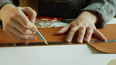 Bir ayakkabıcı onu kesmek için büyük bir parça hakiki derinin üzerine bir kalem ile bir çizgi çizer. Özel ayakkabılar yaratma süreci.