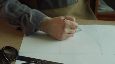 Terzinin eli kalemle yazar ayakkabısının şeklini kağıda çizer..