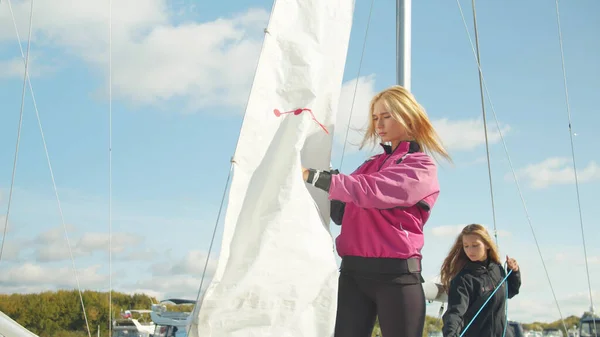 The womens yacht team in the dock jointly puts the mainsail on the mast of a white sports yacht for the North sea regatta. — Stock Photo, Image