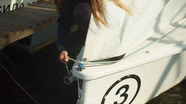 Για να συμμετάσχει σε μια ιστιοπλοΐα regatta, ένα όμορφο κορίτσι προετοιμάζει ιστιοπλοϊκό σκάφος της, ελέγχει τον εξοπλισμό. Σε αργή κίνηση — Φωτογραφία Αρχείου