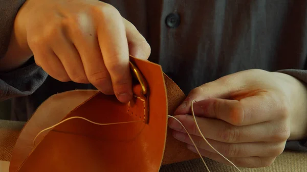 Un tanneur professionnel coud un accessoire sur un sac en cuir véritable. Gros plan, ralenti. — Photo