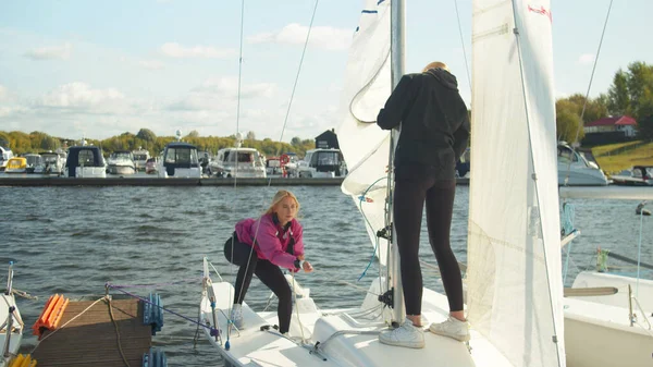 Teamwork of young athletes. Girls together raise the sail on their own fast sports yacht. — Stock Photo, Image