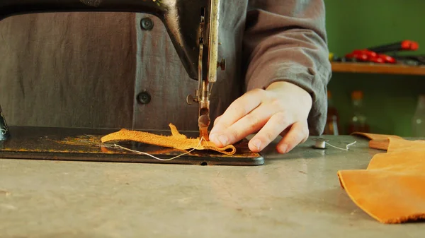 Un tailleur en atelier fabrique un sac exclusif en cuir véritable à l'aide d'une machine à coudre. — Photo