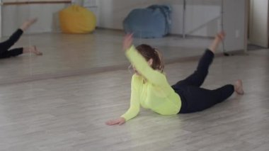 Dans okulundaki grup çalışmasından önce genç bir dansçının ısınması ve esnemesi. Arka virajlı Yoga Asan. Yavaş çekim etkisi.