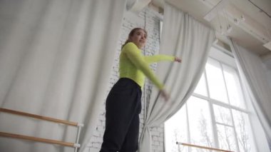 Genç, güzel bir kız modern koreografi ile dans ediyor, farklı stillerin elementlerini birleştiriyor, alttan bakıyor.