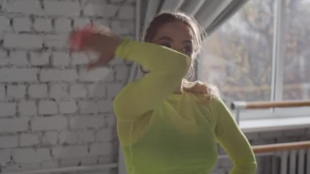 Energisk vogue dans från en vacker flicka mot en tegelvägg och fönster bakgrund, flicka leende, porträtt, närbild — Stockvideo