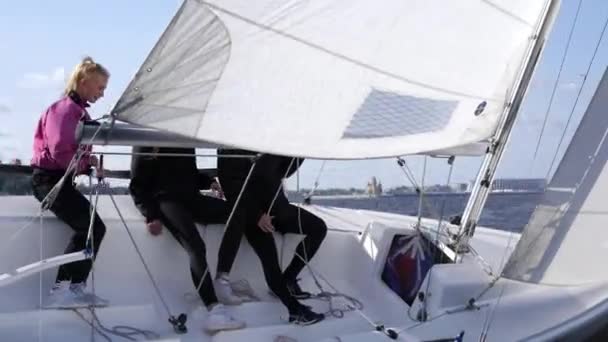 Во время парусной регаты, три спортсмена сидят на левой стороне лодки для баланса — стоковое видео