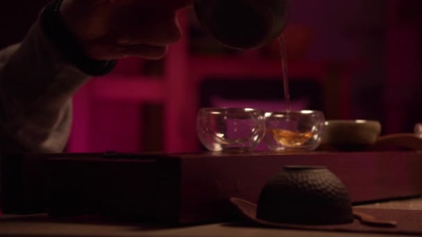 Um encontro romântico numa sala de chá sossegada. Um homem derrama chá chinês natural em uma xícara de meninas de um bule de porcelana. — Vídeo de Stock