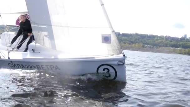 Un joven encantador y dos hermosas chicas viajan en un yate blanco en el río en otoño en cámara lenta — Vídeos de Stock