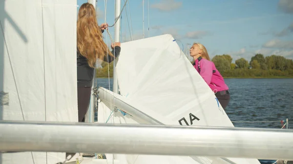 During the preparation for the sailing regatta young athletes girls prepare gear and sail in the dock. Slow motion. — Stock Photo, Image