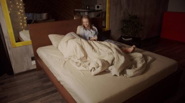 Genç bir kız film izliyor ve yatakta yatarken uzaktan bilgisayarla çalışıyor. Koca, karısının yanında battaniyenin altına uzanıyor. Karantina sırasında kendini izole etme.