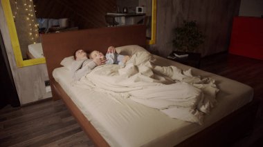 Genç bir çift sabahın erken saatlerinde yatakta uyur. Koca nazikçe karısına sarılıyor. Yatak odasının içi, yaşam tarzı..