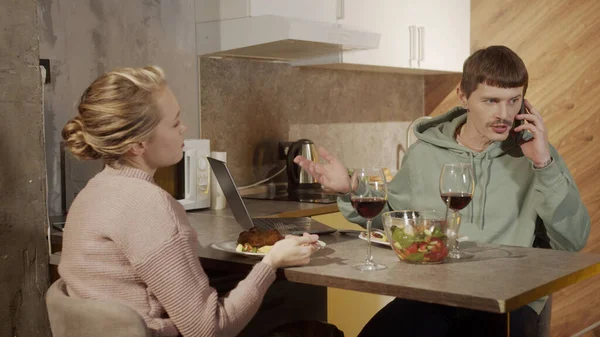Мужчина прерывает семейный ужин на кухне, чтобы ответить на важный телефонный звонок. Он перегружен работой и не обращает внимания на жену.. — стоковое фото