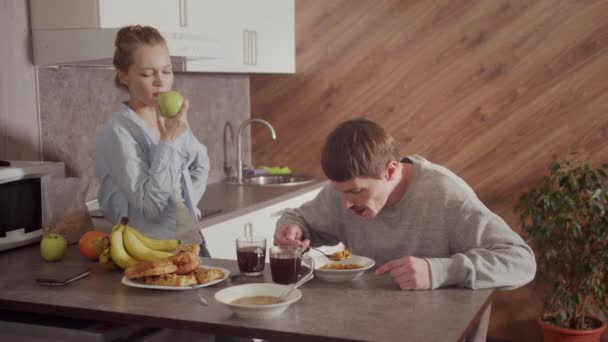 Flickan lagade middag åt sin man. Killen äter soppa och dricker kaffe. Flickan äter ett grönt äpple och pratar.. — Stockvideo