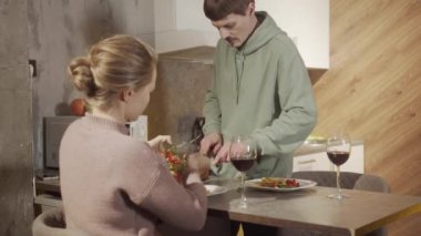 Genç evli bir çift tabağa yemek koyar, yemek sırasında birbirlerine bakarlar.