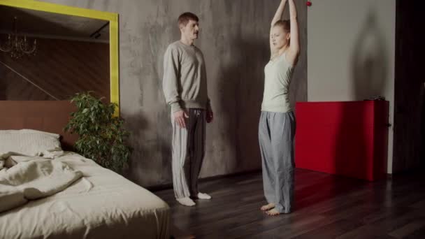Trener uczy młodą klientkę, jak wykonywać najpopularniejsze asany jogi w domu. — Wideo stockowe