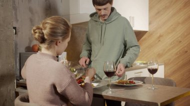 Genç evli bir çift tabağa yemek koyar, yemek sırasında birbirlerine bakarlar.