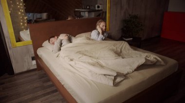 Bir erkek ve bir kadın evdeki bir yatakta uyurlar. Bir kız sabah akıllı telefonundan gelen bir telefonla uyanır ve telefona cevap verir..