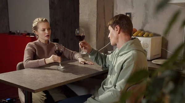 Ein junges Ehepaar trinkt in der Küche Rotwein, stößt an und klimpert mit Gläsern — Stockfoto