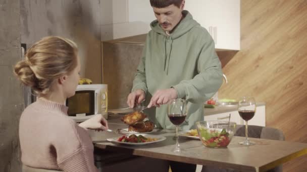 A young caring husband puts food on his wifes plate and his own while celebrating a family date — Video Stock