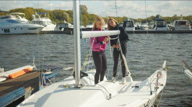 İki genç arkadaş bir yatla seyahat ediyorlar. Teçhizatı bağlarlar ve yelkenleri açarlar. Spor turizmi kavramı.