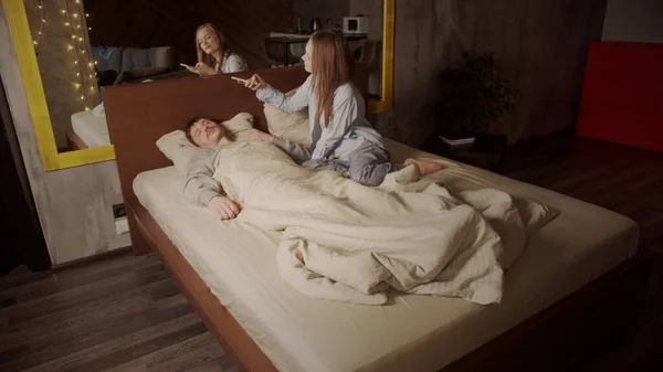Молодая жена фотографирует своего любимого спящего мужа на смартфоне, лежащего в постели. Ранним утром, молодая пара в спальне. — стоковое фото