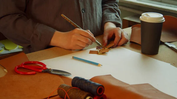 Bureau d'un tanneur qui fabrique des produits en cuir exclusifs. Sur la table se trouvent des fils de restaurant, des morceaux de cuir et une tasse de café en papier.. — Photo