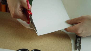 Terzi atölyesinde yeni moda tasarımı için makasıyla kağıt desenler yapıyor..