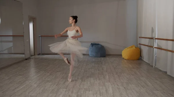 Charmante ballerina in de danszaal voor de spiegel in een prachtige jurk pirouettes doen — Stockfoto