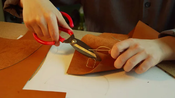 Un tanneur expérimenté dans le processus de création d'un sac à main pour femmes. Coupe l'excès de fil et scelle la pointe avec un briquet. — Photo