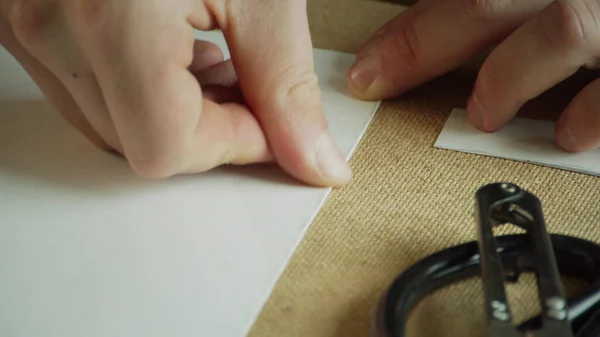 Close-up van de meesters handen maken een nette en precieze vouw van papier voor het maken van patronen. Video in slow motion. — Stockfoto