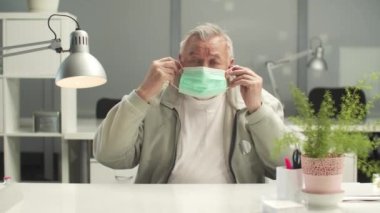 Yaşlı yönetici korku içinde bir maske takar ve konuşmaya devam eder.