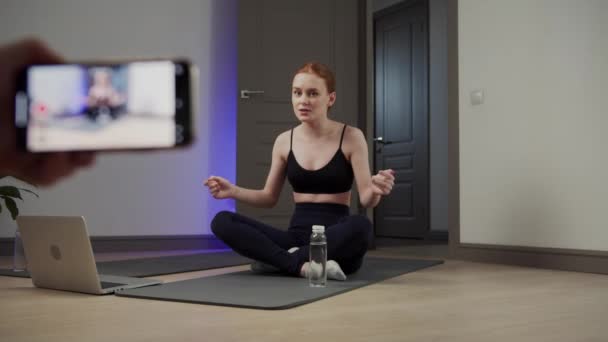 Flicka idrottsman skriver en video blogg på telefonen och mediterar — Stockvideo