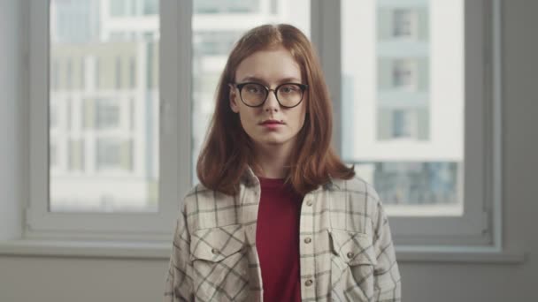 Ein junges Mädchen mit Brille steht in einer Wohnung — Stockvideo