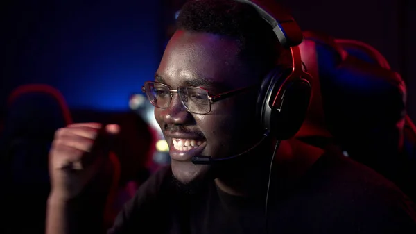 An african guy wearing headphones and glasses leads an online stream during the computer games championship — Stock Photo, Image