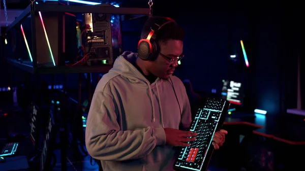 Before the online gaming tournament in the computer room, an african-american gamer received a new keyboard, looks at it and likes it