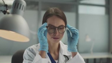 Yorgun genç kız doktor gözlüğünü yüzünden çıkarır ve yavaşça kameraya bakar..