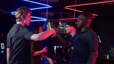 Beyazlar ve Afrikalılar, atıcılık turnuvasındaki zorlu zaferden sonra birbirlerine beşlik çakar ve el sıkışırlar.